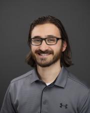 Photo of Brett doze smiling against dark background