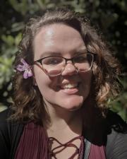 Photo of Maggie, with glasses and a flower in her hair